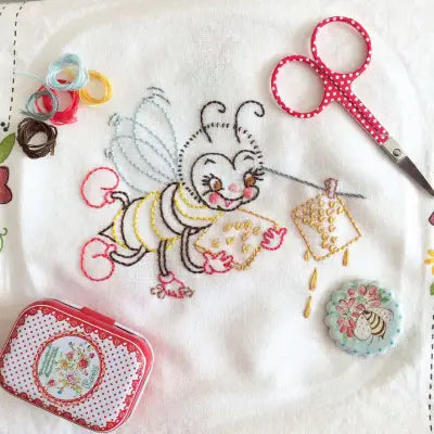 Hand-embroidered Busy Bee design in yellow and black on white fabric by Aunt Martha’s