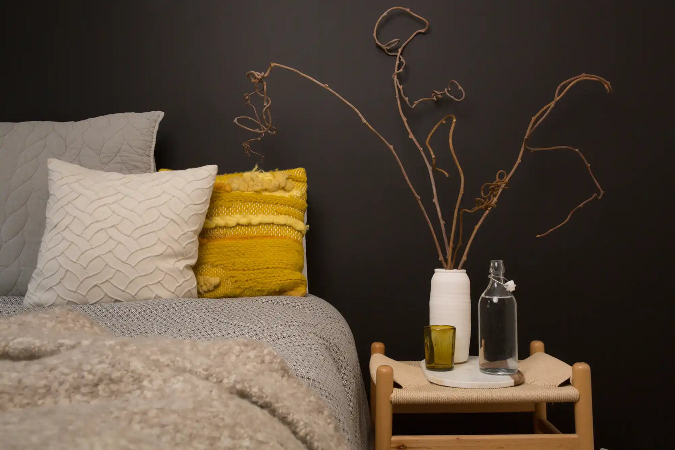 Cozy bed with gray bedding and contrasting yellow and white throw pillows.